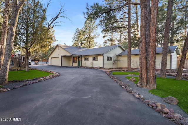 ranch-style home featuring a front lawn, an attached garage, and driveway