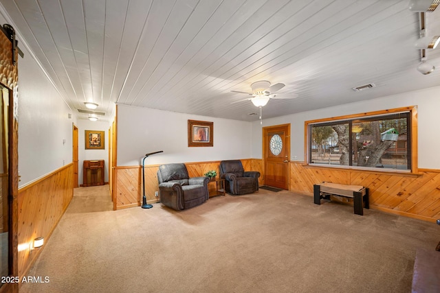 living area featuring a wainscoted wall, visible vents, and wooden walls