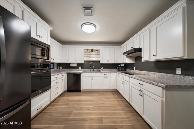 kitchen featuring light wood finished floors, black appliances, under cabinet range hood, white cabinetry, and a sink