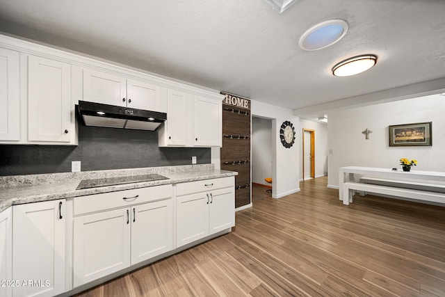 kitchen with baseboards, under cabinet range hood, light wood-type flooring, white cabinetry, and black electric cooktop