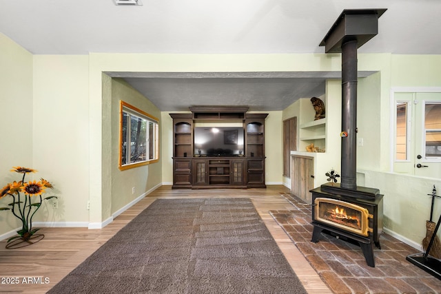 living area with baseboards, wood finished floors, and a wood stove