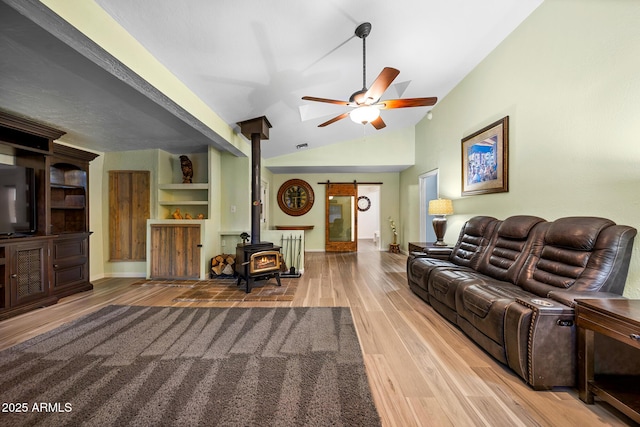 living room with high vaulted ceiling, wood finished floors, baseboards, ceiling fan, and a wood stove