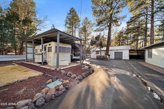 view of outdoor structure with a detached carport, aphalt driveway, and an outbuilding