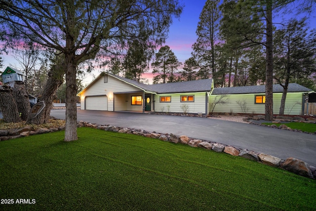 view of front of property with aphalt driveway, a yard, and an attached garage