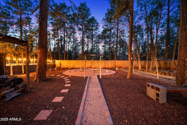 yard at dusk featuring a playground and fence