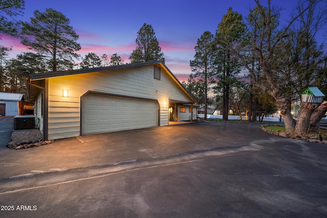 property exterior at dusk with aphalt driveway and an outdoor structure