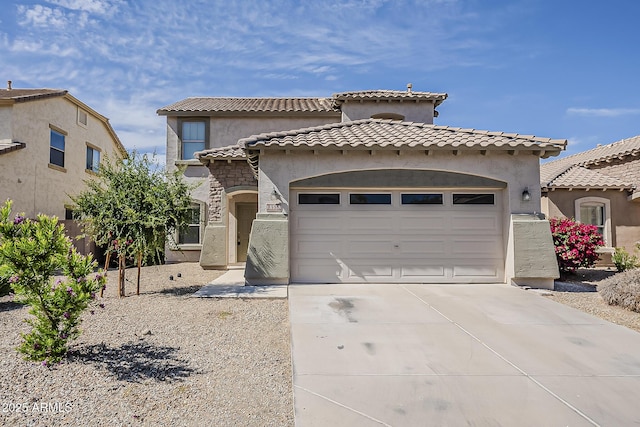 mediterranean / spanish house with concrete driveway, stucco siding, a tile roof, and an attached garage