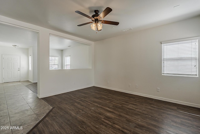 empty room with ceiling fan, baseboards, dark wood-style floors, and visible vents