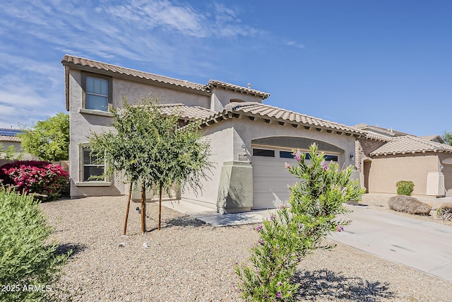 mediterranean / spanish house with an attached garage, stucco siding, and a tiled roof