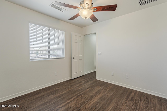 spare room featuring visible vents, baseboards, a ceiling fan, and dark wood-style floors