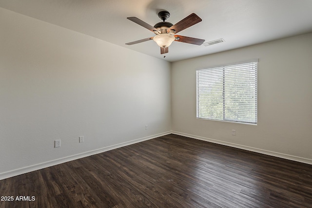 spare room with dark wood-style flooring, baseboards, a ceiling fan, and visible vents