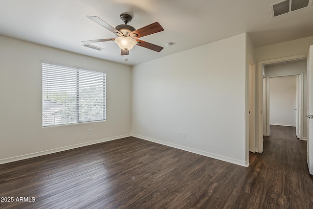 empty room featuring a ceiling fan, baseboards, dark wood-style floors, and visible vents