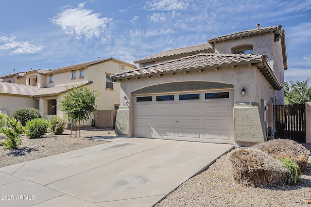 mediterranean / spanish home featuring concrete driveway, an attached garage, stucco siding, and fence