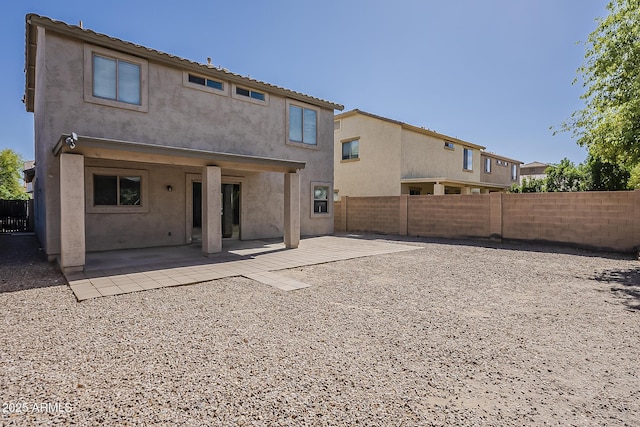 rear view of property with stucco siding, a patio area, and a fenced backyard