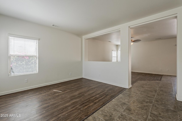 spare room featuring dark wood-style flooring, visible vents, baseboards, and ceiling fan