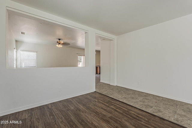 spare room featuring baseboards, visible vents, a ceiling fan, and wood finished floors