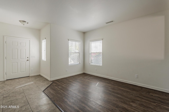 foyer featuring baseboards, visible vents, and wood finished floors