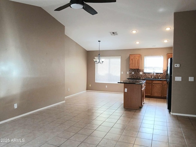 kitchen with refrigerator, sink, hanging light fixtures, vaulted ceiling, and a kitchen island