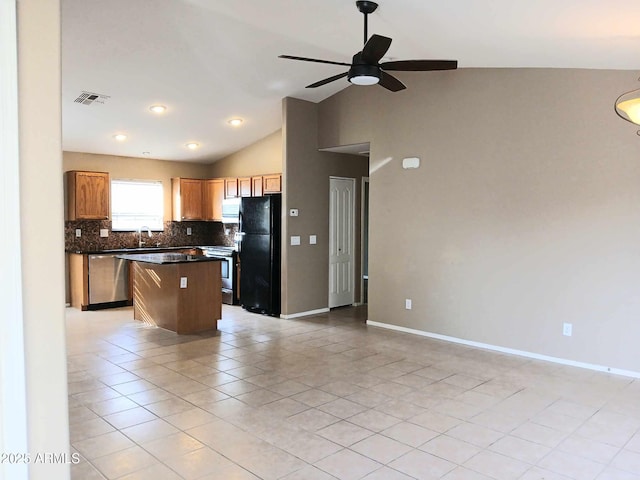 kitchen featuring stainless steel appliances, sink, light tile patterned floors, a center island, and lofted ceiling