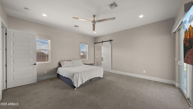 bedroom featuring ceiling fan, a barn door, and light carpet