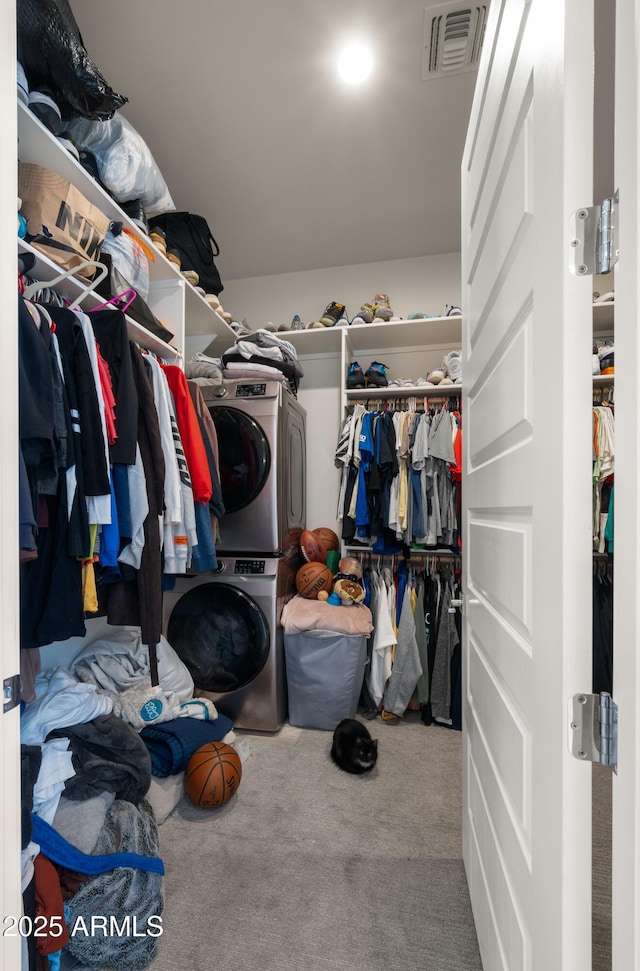 walk in closet with stacked washer and dryer and carpet flooring