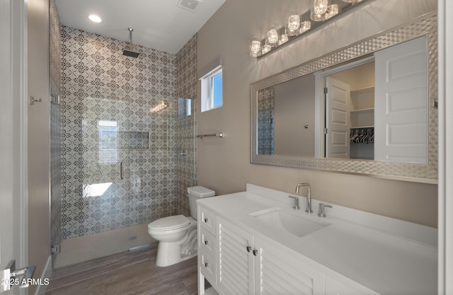 bathroom with vanity, toilet, hardwood / wood-style flooring, and a shower with door