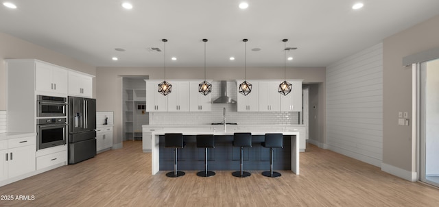 kitchen with white cabinetry, backsplash, decorative light fixtures, wall chimney range hood, and high end black refrigerator