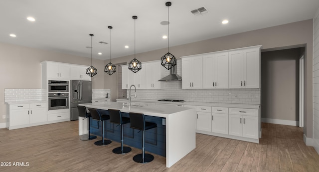 kitchen featuring decorative light fixtures, white cabinetry, a kitchen island with sink, and tasteful backsplash