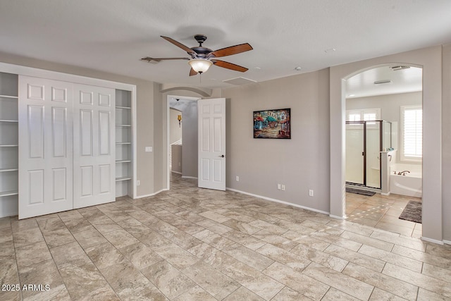 7252 E Nance St, Mesa, AZ 85207 - unfurnished bedroom featuring arched walkways, a closet, connected bathroom, and a ceiling fan