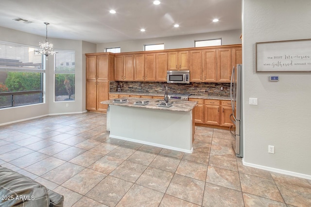 7252 E Nance St, Mesa, AZ 85207 - kitchen featuring appliances with stainless steel finishes, backsplash, light stone counters, a chandelier, and a kitchen island with sink