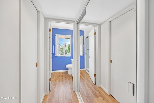 hallway featuring light wood finished floors, attic access, and baseboards