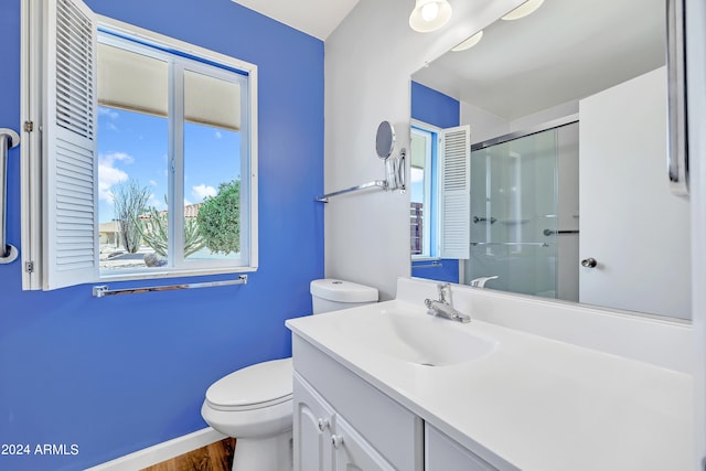 bathroom with baseboards, toilet, a shower with shower door, wood finished floors, and vanity