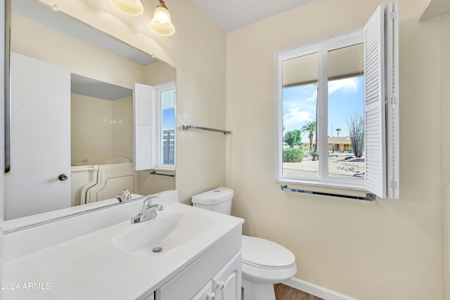 bathroom with vanity, toilet, wood finished floors, and baseboards