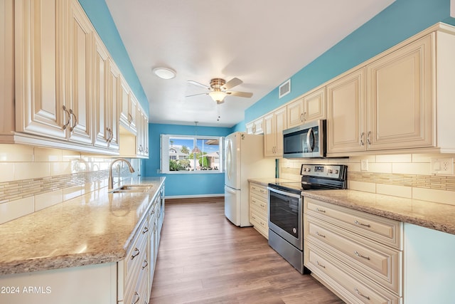 kitchen featuring wood finished floors, baseboards, a sink, decorative backsplash, and stainless steel appliances