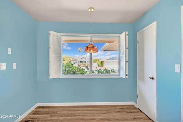 unfurnished dining area featuring wood finished floors and baseboards