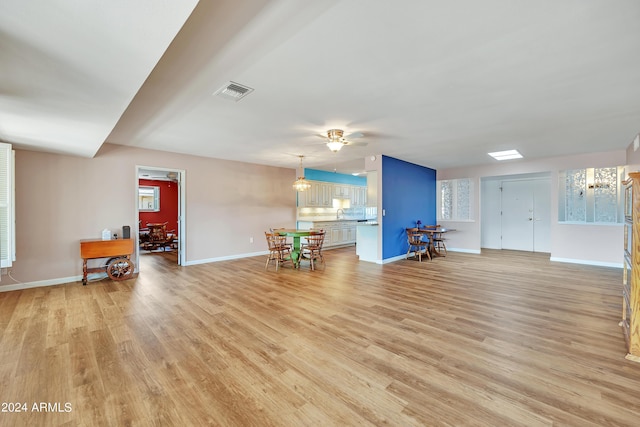 interior space with visible vents, light wood-style flooring, a ceiling fan, and baseboards