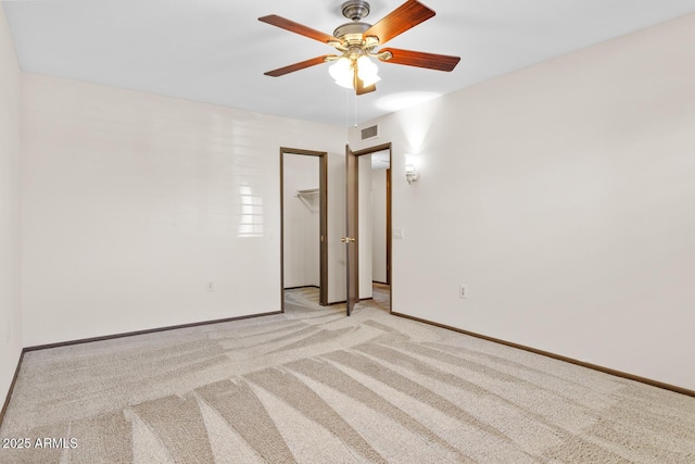 empty room featuring ceiling fan, visible vents, light carpet, and baseboards