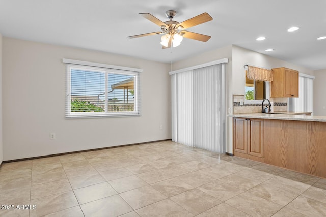 kitchen featuring a ceiling fan, tasteful backsplash, light stone countertops, a sink, and recessed lighting