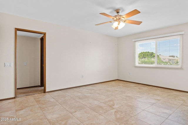 empty room featuring a ceiling fan, baseboards, and light tile patterned flooring