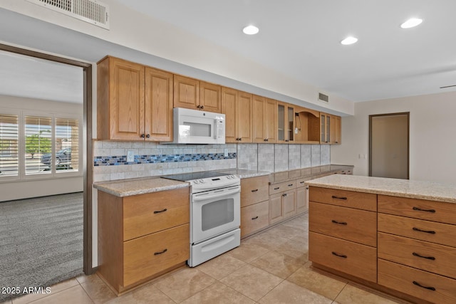 kitchen featuring light stone countertops, white appliances, decorative backsplash, visible vents, and glass insert cabinets