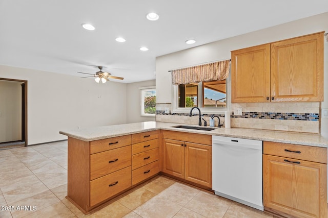 kitchen featuring white dishwasher, tasteful backsplash, a sink, light stone counters, and a peninsula