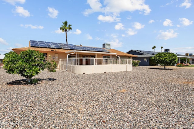 back of house featuring solar panels