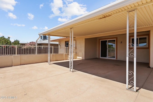 view of patio featuring central AC unit, fence, and an attached carport