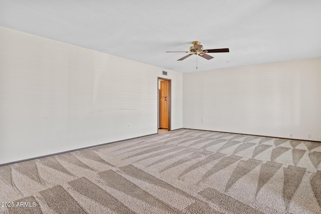 carpeted empty room with visible vents, baseboards, and ceiling fan