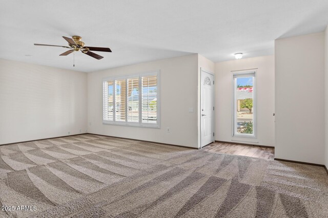 unfurnished room featuring baseboards, carpet flooring, a ceiling fan, and a wealth of natural light