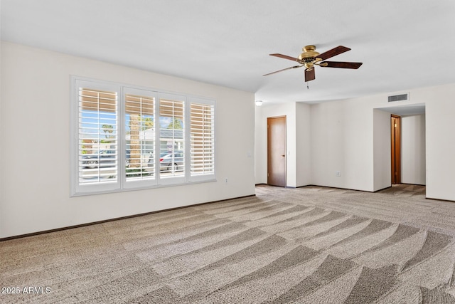 empty room with visible vents, a ceiling fan, carpet, and baseboards