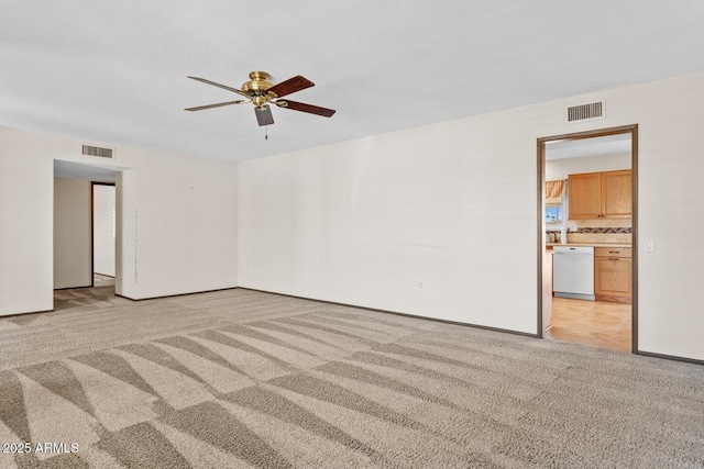 empty room with baseboards, light carpet, a ceiling fan, and visible vents