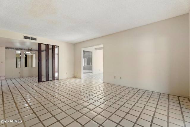 tiled empty room featuring a textured ceiling