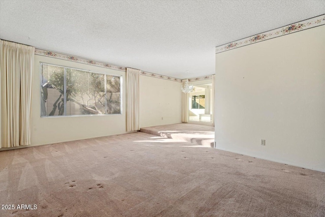 empty room with a textured ceiling, carpet flooring, and a healthy amount of sunlight