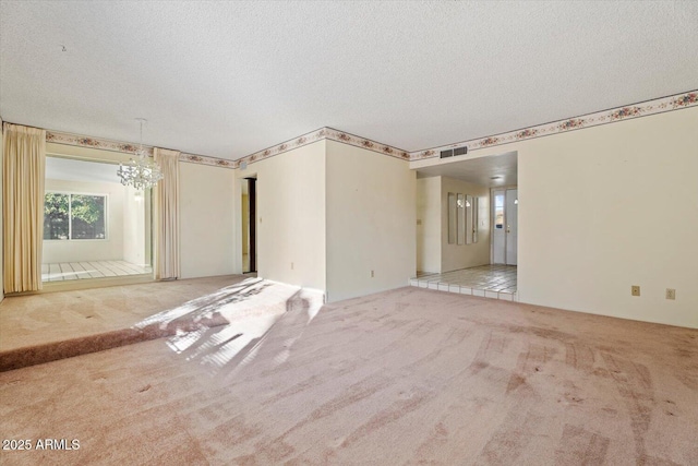 carpeted empty room featuring a textured ceiling and a chandelier